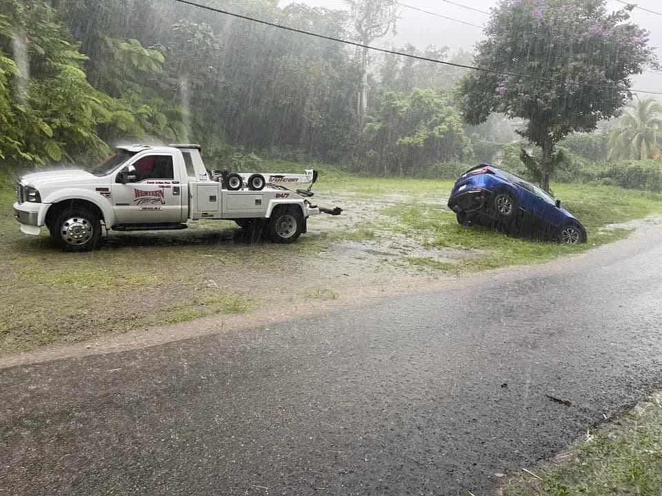 Grúa de Western Towing rescatando un carro fuera de la carretera bajo lluvia en Mayagüez, Puerto Rico