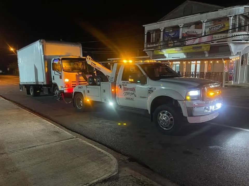 Grúa de Western Towing remolcando un camión de carga de noche en Aguadilla, Puerto Rico